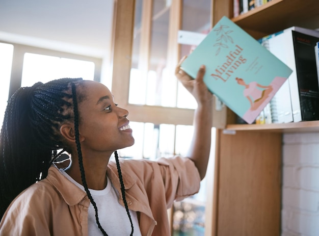 幸せな黒人女性と家の図書館の本は、穏やかなリラックスとコンテンツの読書の日を過ごす準備ができています 精神的健康のために家でマインドフルネスの生きた本を持っているジャマイカ出身の人の幸せな笑顔
