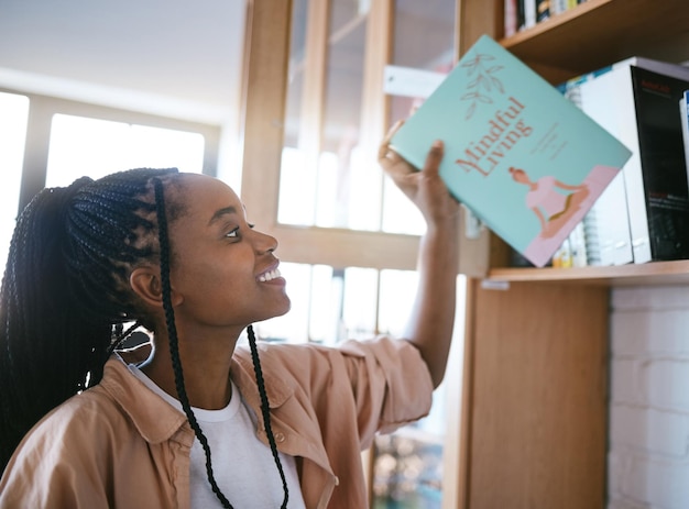 Black woman happy and home library books ready to spend a calm relax and content reading day Happy smile of a person from Jamaica holding a mindfulness living book in a house for mental health