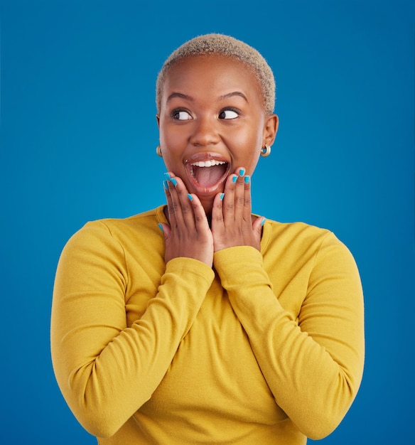 Black woman happy and surprise face in studio for fashion youth or notification by blue background young african girl model or happiness with excited wow announcement or deal with hands by mouth
