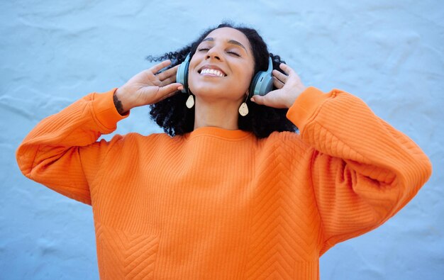 Foto cuffie da donna di colore e ascolta la musica libertà di rilassarsi con benessere e streaming audio felicità senza preoccupazioni con radio o podcast mentalità e tranquillità con playlist su sfondo blu