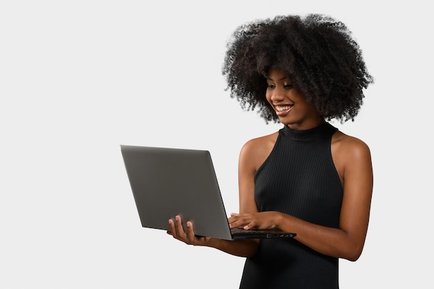 black woman holding a computer while looking and smiling at the computer screen on white background