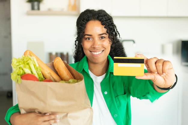 Black Woman Holding Grocery Shopping Bag Showing Credit Card Indoors