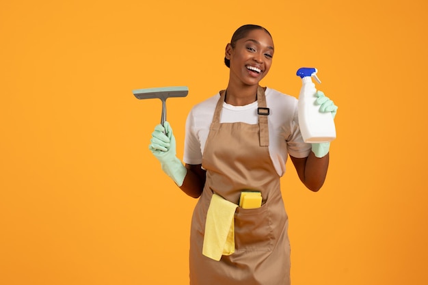 Black woman holds brush for window cleaning and detergent studio