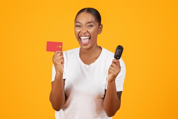 Black woman holds new car key and credit card studio