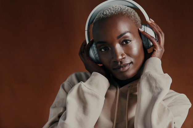 black woman hoodie and headphones in studio portrait for training music or fitness by background person model and style with jacket streetwear and streaming with clothes for winter in nigeria