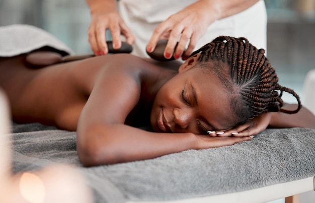 Photo black woman hot stone massage and masseuse hands and zen with holistic therapy and spa treatment calm peace of mind and female healing and stress relief with self care at wellness resort