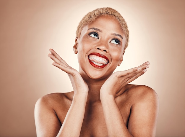 Black woman makeup and face with red lipstick on a brown background for beauty cosmetics Aesthetic model with hands thinking of idea in studio with funny smile and facial skin glow with bold lips