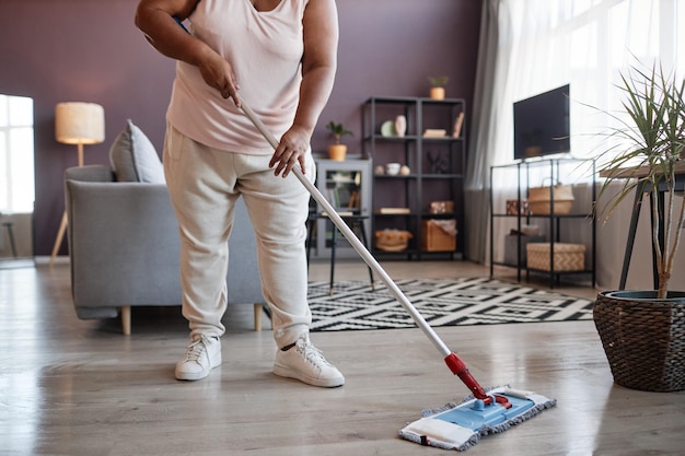 Black woman mopping floors while cleaning house copy space