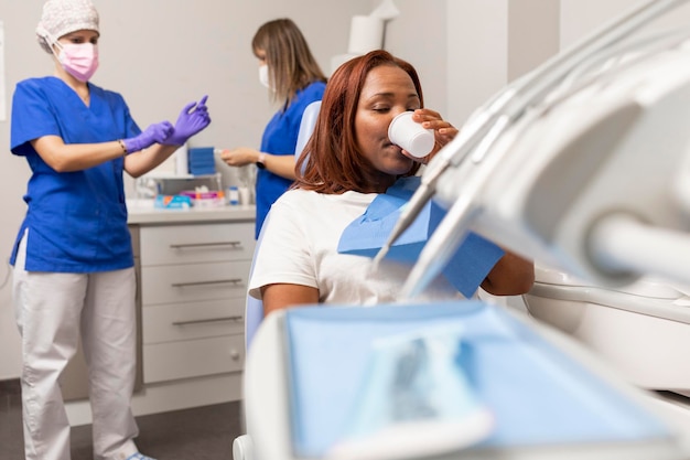 Black woman patient rinses her mouth before the dental treatment she is going to receive