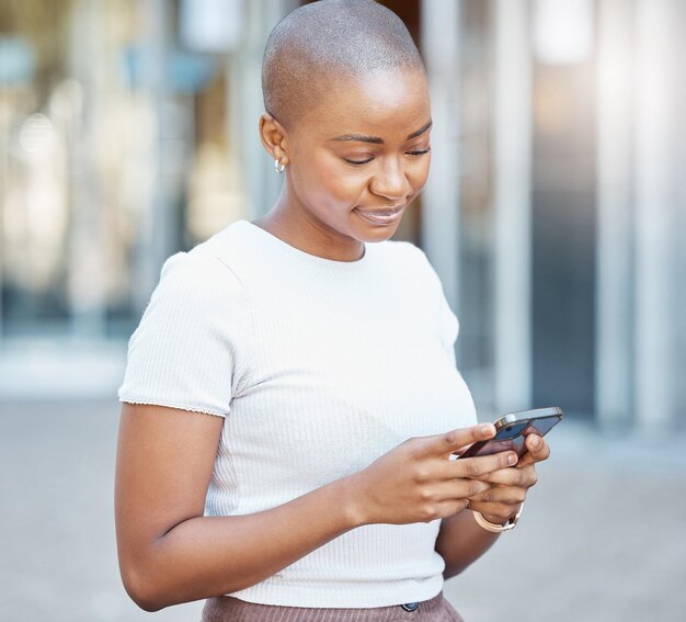 Black woman phone and smile in the city for social media texting or chatting in the outdoors happy african american female on smartphone typing talking and smiling for 5g connection in urban town