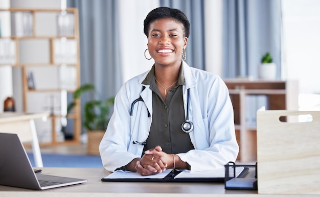 Black woman portrait and doctor in office for medical services advice and consulting in clinic Happy female therapist healthcare worker and consultant at desk in hospital for wellness management