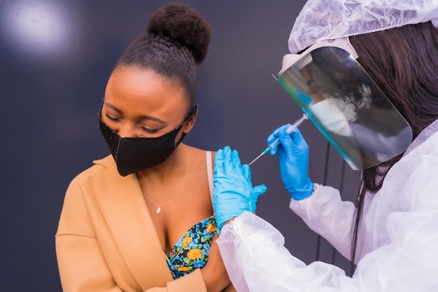 医師によるコロナウイルスワクチンの注射を受けている黒人女性