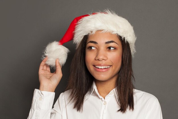 Black woman Santa smiling on gray background