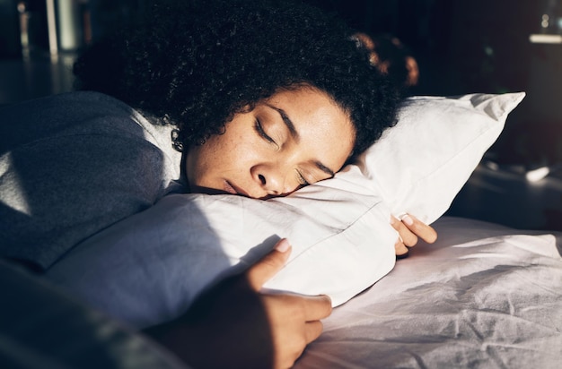 Black woman sleeping and pillow in morning for peace quiet and rest or relax in home bedroom Person on bed to dream or for calm sleep with sleepy or stress relief for health and wellness