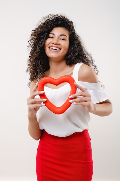 Black woman smiling with heart shaped red figure isolated