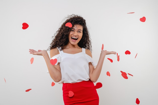 Black woman smiling with heart shapes flying in the air isolated