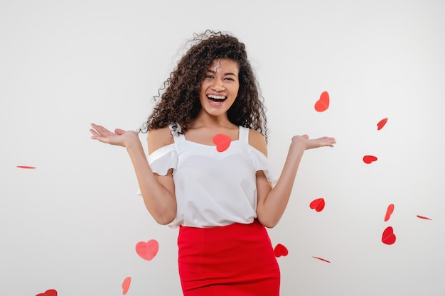 Black woman smiling with heart shapes flying in the air isolated