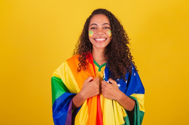 Donna di colore, tifosa di calcio brasiliana, con bandiera brasiliana e bandiera lgbt, lotta per la diversità