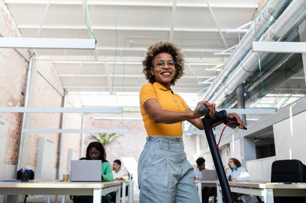 Black woman standing the office with electric scooter looking at camera Sustainable lifestyle