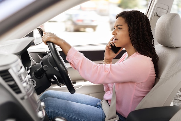 Donna di colore che parla al cellulare mentre si guida l'auto