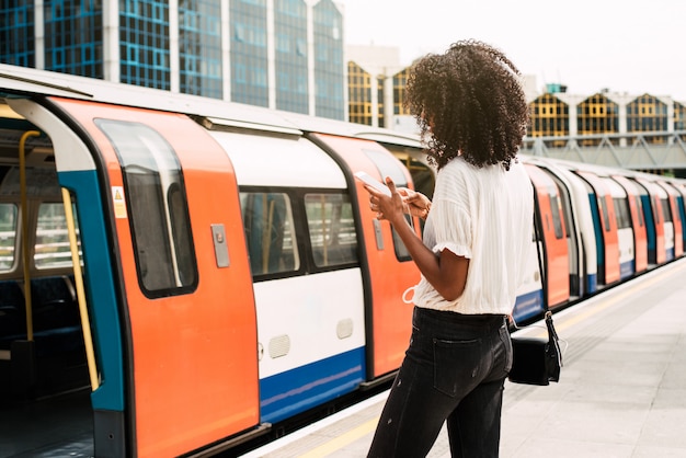 Donna di colore che per mezzo del telefono cellulare a londra sotterranea