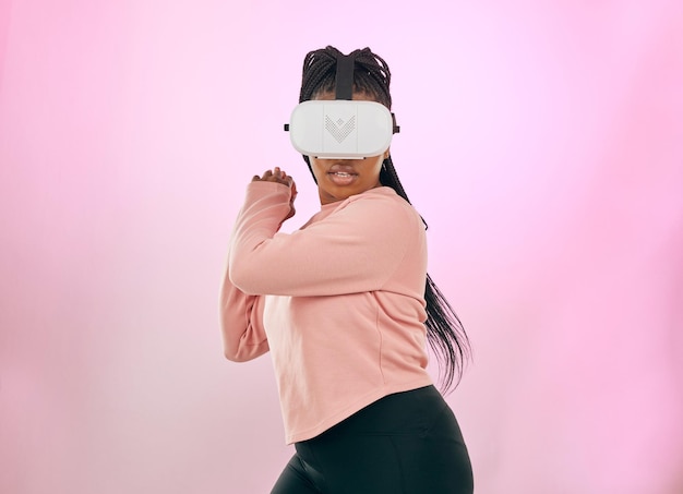 ピンクのスタジオ背景に対する未来的なゲームまたは活動のためのメタバースの黒人女性VRおよびゲーマー将来的にモックアップでヘッドセットを使用した3D仮想現実ゲームのアフリカ系アメリカ人女性