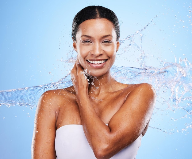 Black woman water splash and woman skincare moisturizing skin natural body wellness and liquid detox cleaning routine Sustainable cosmetics health washing skin and smile on a blue wall background