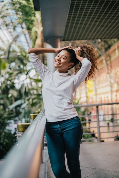 Black woman with afro hair touches her curly hair.