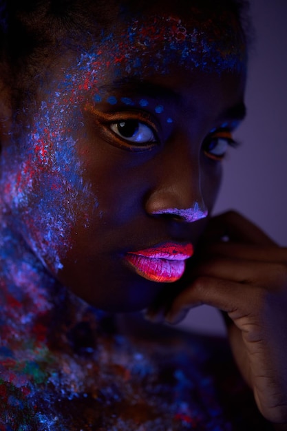 Black woman with body art glowing in ultraviolet light portrait\
of beautiful woman painted in fluore...