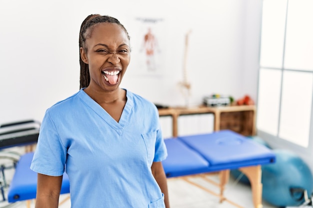 통증 회복 클리닉에서 머리를 땋은 흑인 여성은 재미있는 표현 감정 개념으로 행복해하며 혀를 내밀고 있습니다