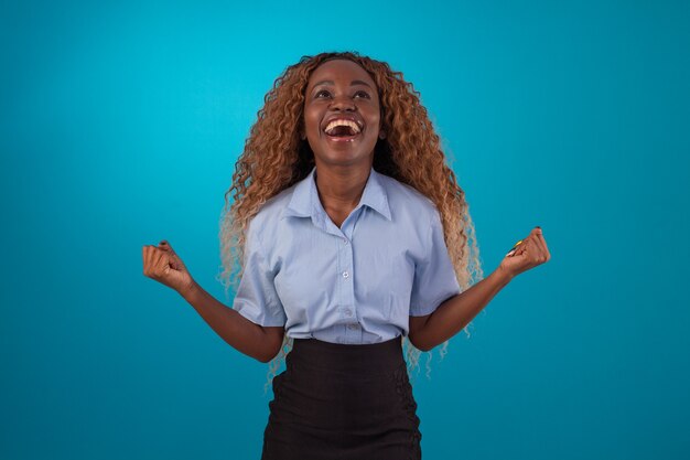 Black woman with curly hair in studio photo wearing blue shirt and black skirt and making various facial expressions.