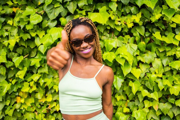 Black woman with sunglasses gesturing to be okay facing the camera outdoors