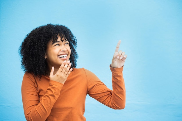 Black woman wow face and pointing hands in studio for news announcement or notification by blue background African gen z girl young model and fashion with surprise hand sign with excited laugh