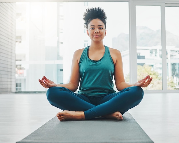 Young fit Black woman in seated balancing yoga pose exercising on