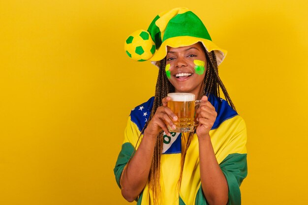 Black woman young brazilian soccer fan drinking beer and\
celebrating