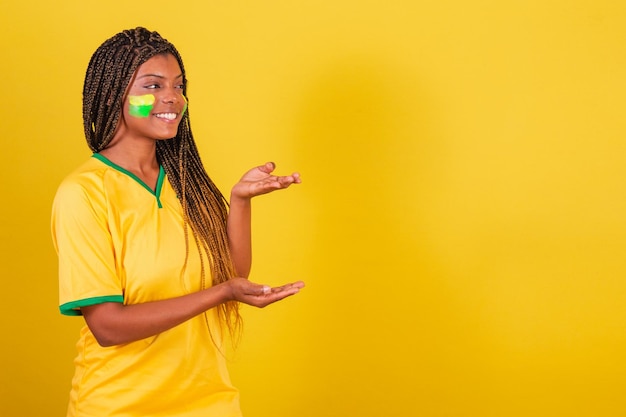 Black woman young brazilian soccer fan presenting something to the right smiling publicity photo