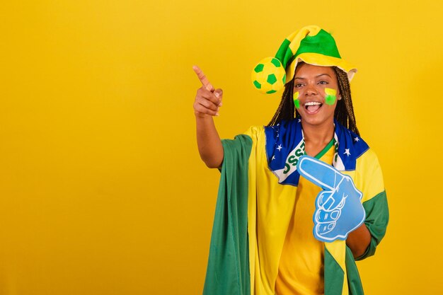 Black woman young brazilian soccer fan using foam finger spotting something in the distance