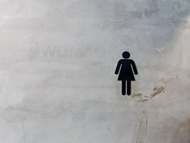 写真 汚いコンクリートの壁に黒人の女性トイレのシンボル