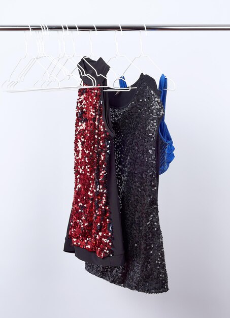 Photo black womens blouses with red and black sequins hanging on a white iron hanger