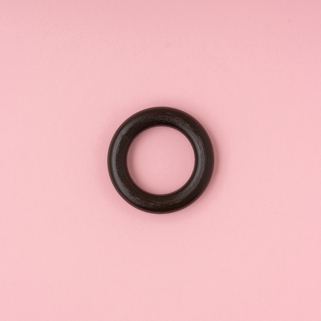 Black wood ring on pink background.