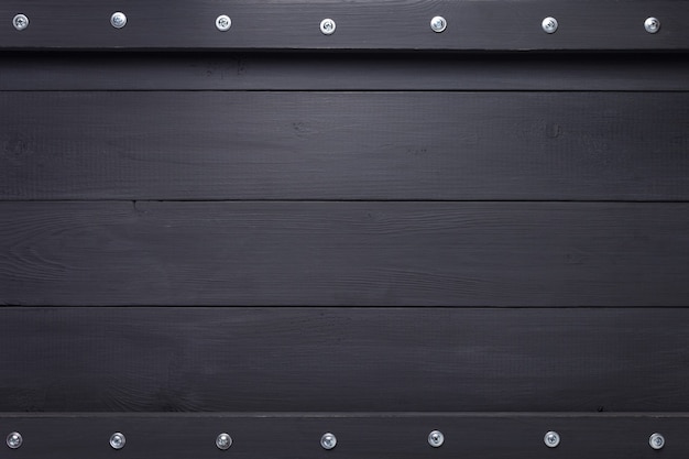 Black wooden background as texture surface with screws