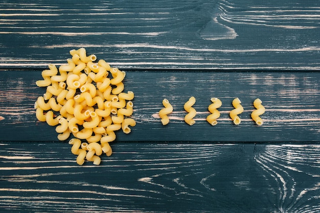 Foto su uno sfondo di legno nero maccheroni un grappolo di pasta