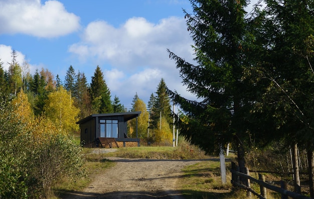 Black wooden cabin in colorful forest in autumn with copy space