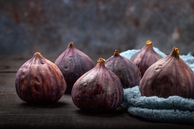 On a black wooden table are the fruits of fresh figs. Beautiful blue fig fruits close up