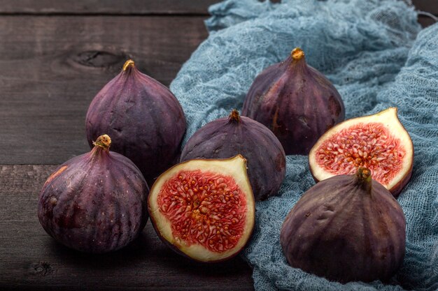 Su un tavolo di legno nero ci sono i frutti di fichi freschi. la bella frutta blu del fico si chiuda