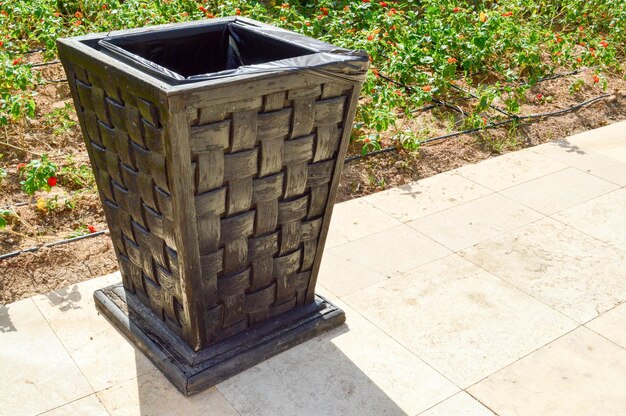 Black wooden wicker trash for discarding garbage to maintain cleanliness is on the stone floor