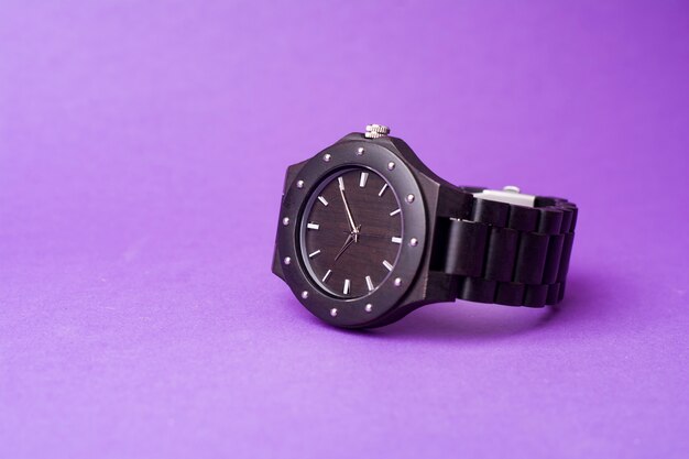 Black wrist watch on purple background