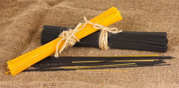 Черные и желтые спагетти на фоне мешковины