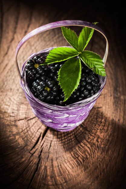 Blackberries in basket on vintage wooden board