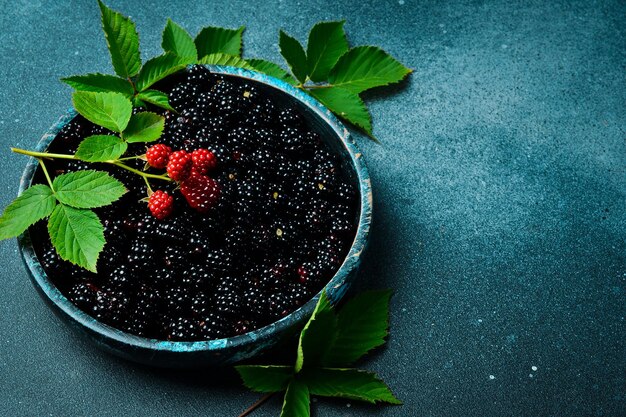 Черные ягоды в миске Свежие черные ягоды и зеленые листья вблизи макрофото Сверху